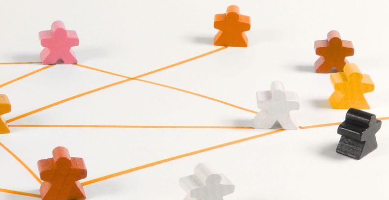 Mehrere Spielfiguren in verschiedenen Farben, verbunden durch orange Linien auf hellem Hintergrund