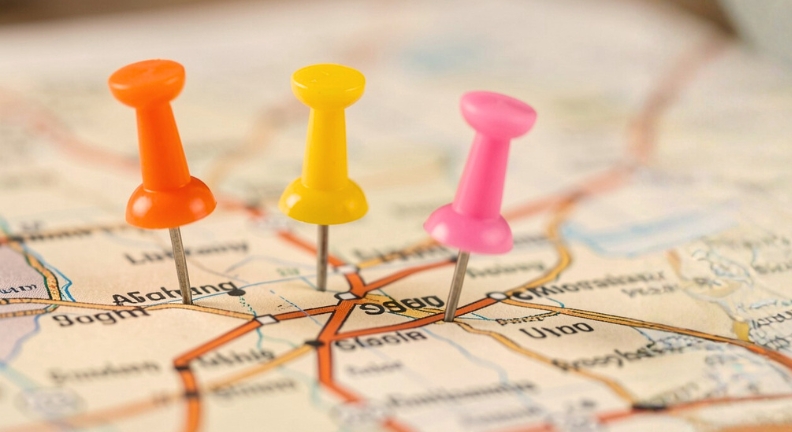 Drei farbige Stecknadeln auf Landkarte mit Ortsnamen und Straßenlinien